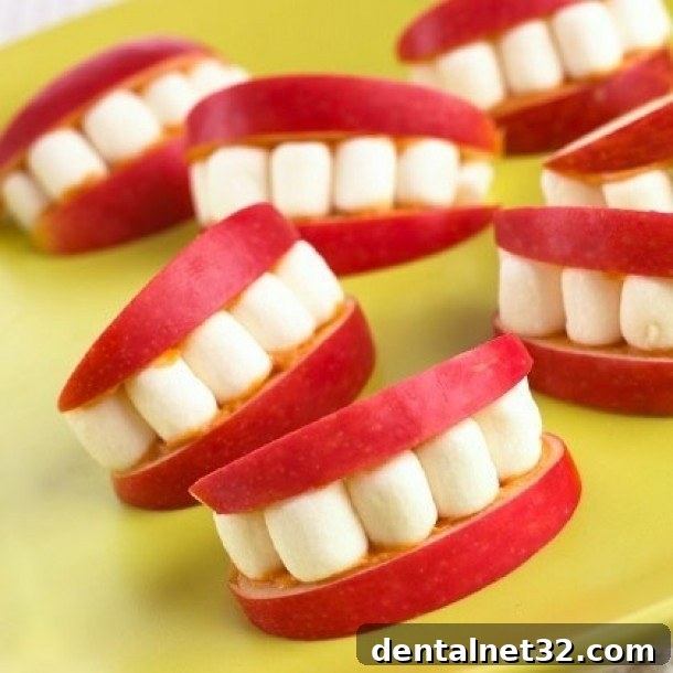 Apple slices with peanut butter and mini marshmallows arranged to look like a mouth with teeth.
