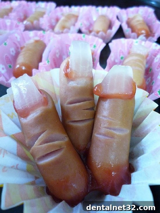 Mini hot dogs prepared to look like severed fingers with an onion fingernail and ketchup blood.