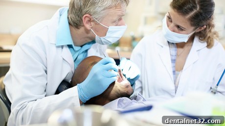A dental school professor guiding a student during a clinical simulation.