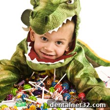 A child in a Halloween costume smiling and holding a pumpkin bucket full of candy.